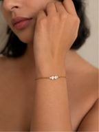 Woman wearing a minimalist gold chain bracelet with petite white baroque freshwater pearls