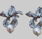 Macro detail showing the intricate textures of handcrafted silver flower earrings and the iridescence of the freshwater pearl attached