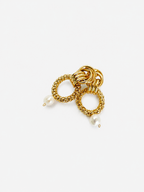 Angled close-up of textured gold double-hoop earrings with organic white baroque pearl drops