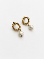 Angled view of gold beaded drop earrings with organic white baroque freshwater pearl drops