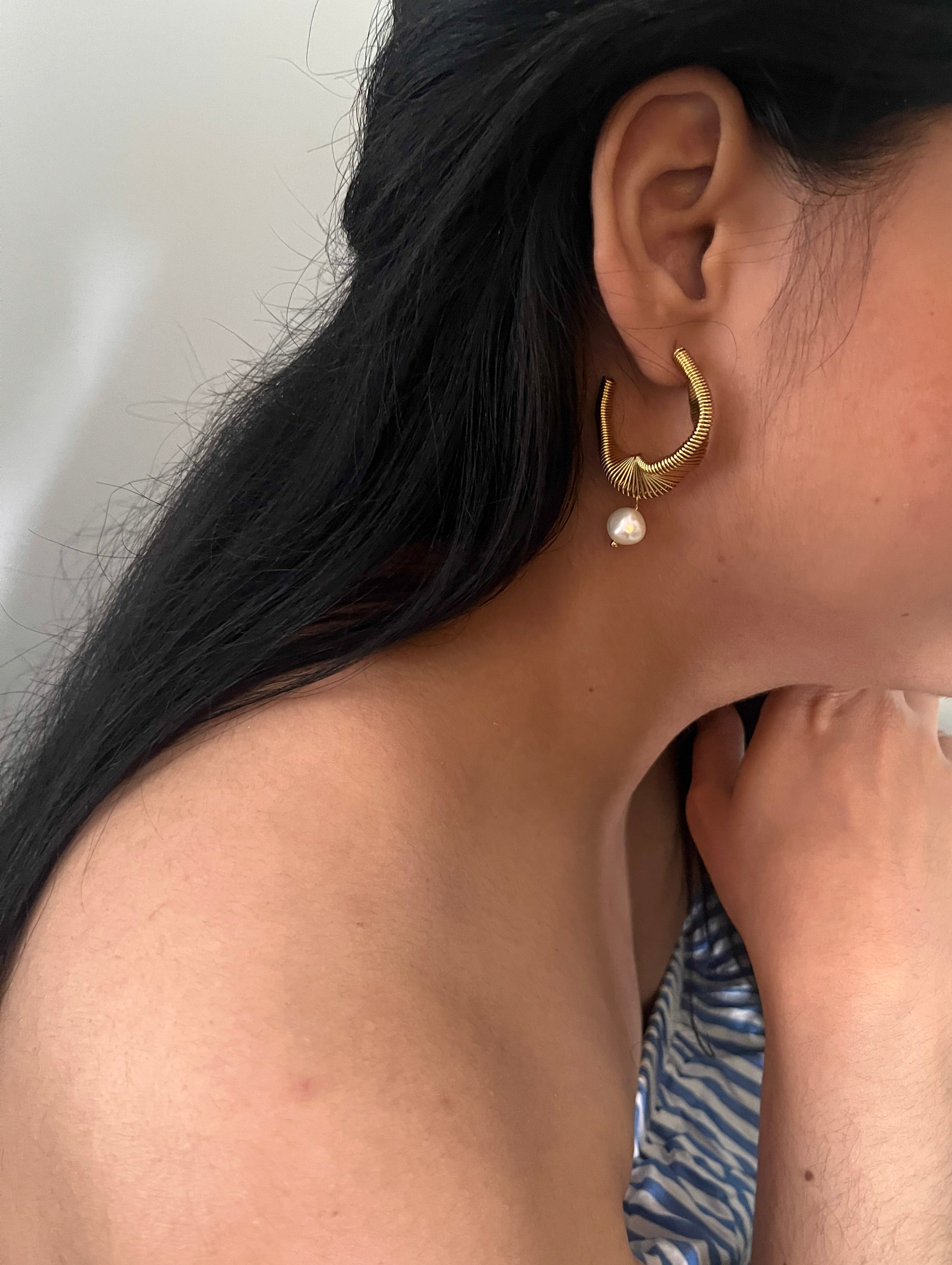 Angled pair of sculptural coiled gold earrings with organic white baroque freshwater pearl drops