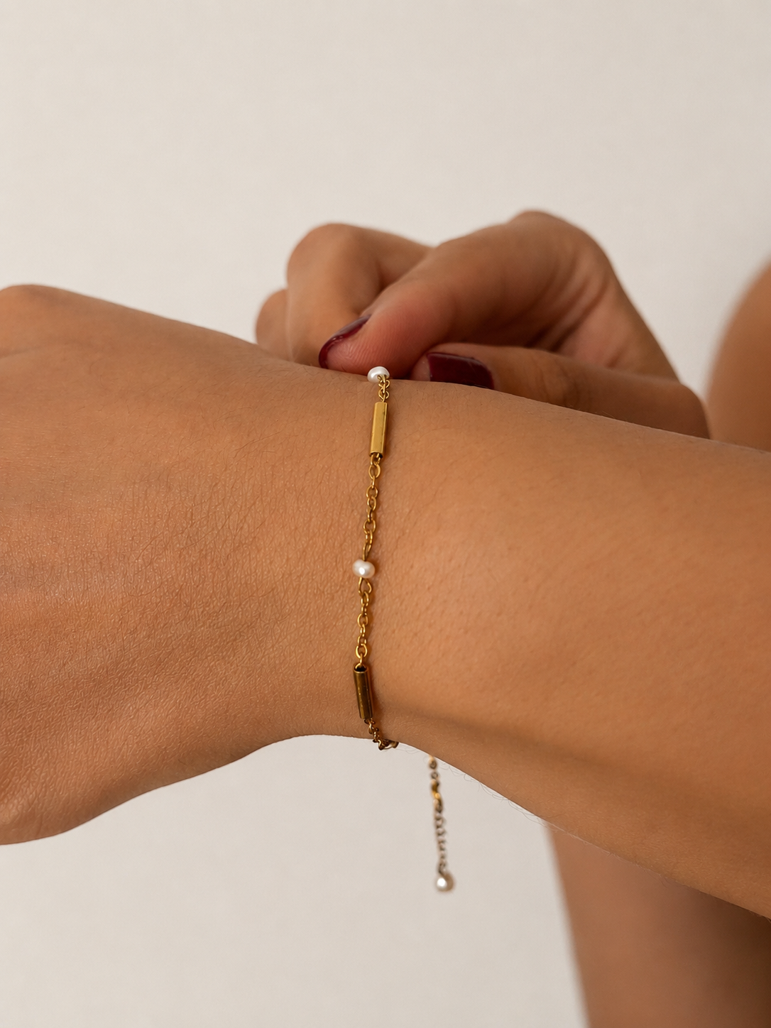 Wrist close-up of a delicate gold bracelet with petite white baroque freshwater pearls and polished gold accents