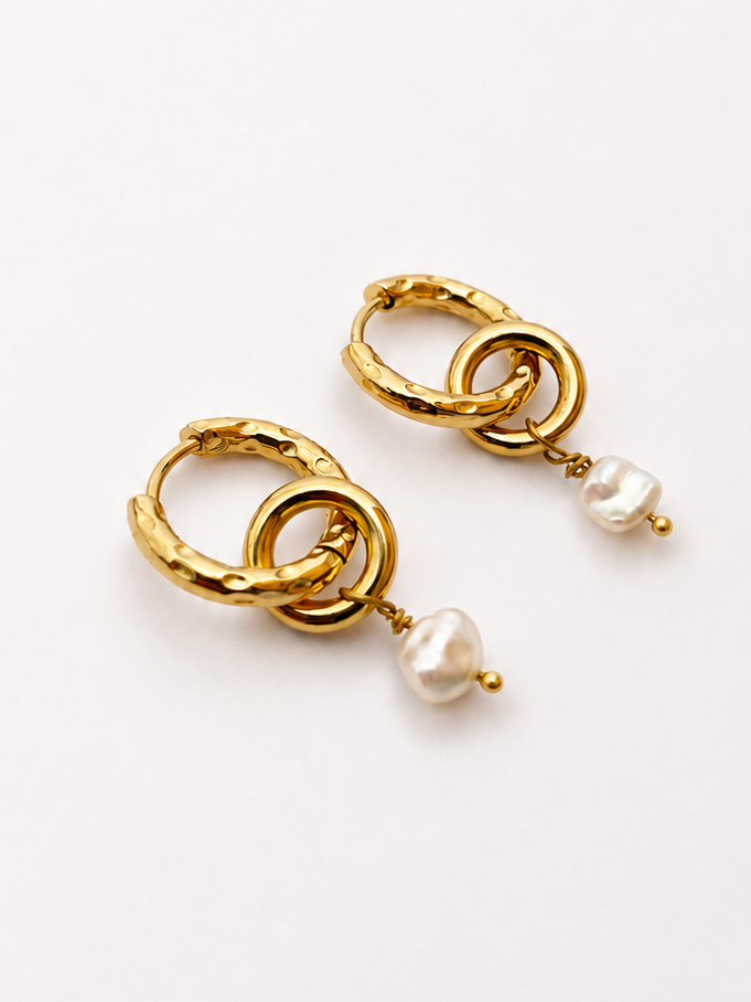 Angled close-up of gold double-hoop earrings with organic white baroque freshwater pearl drops.