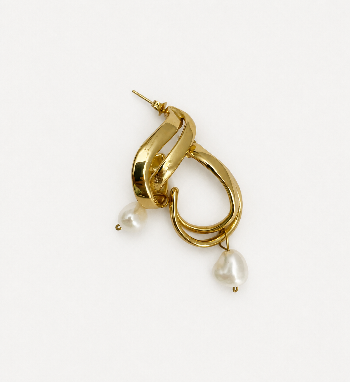 Angled view of sculptural gold double-hoop earrings with white baroque pearl drops