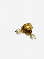 Angled close-up of textured gold earrings with organic white baroque pearl drops