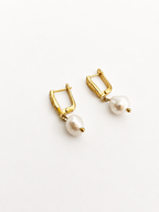Back view of gold drop earrings with white baroque freshwater pearls and hinged clasps.