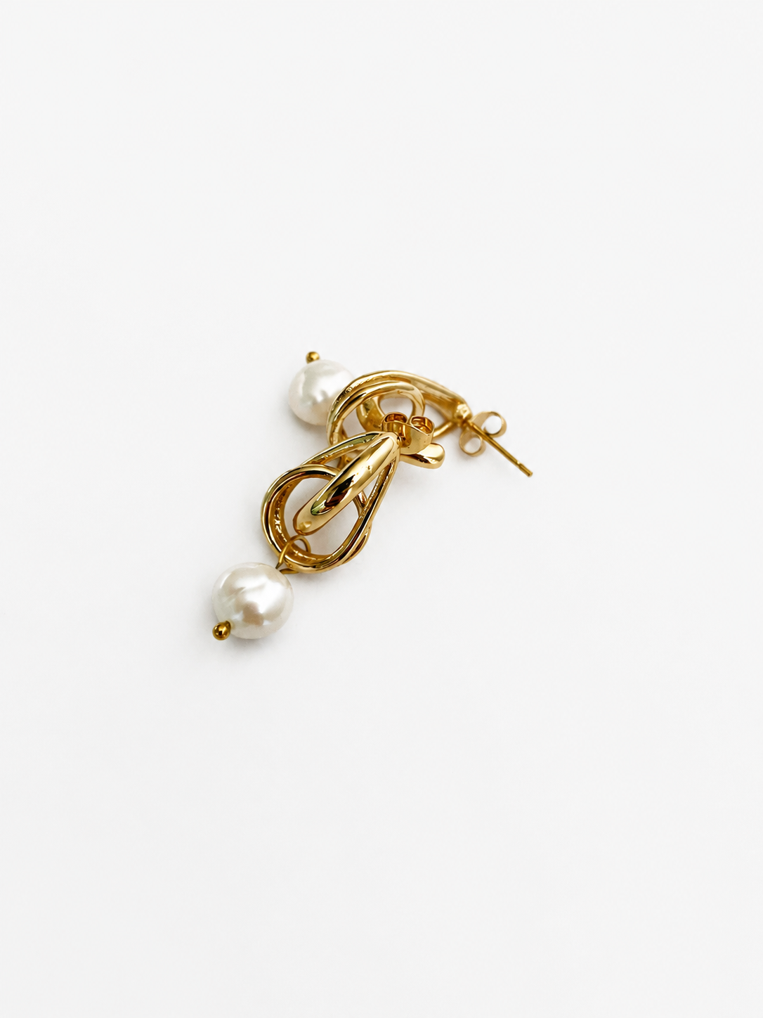 Angled view of gold droplet earrings with organic white baroque freshwater pearl drops.
