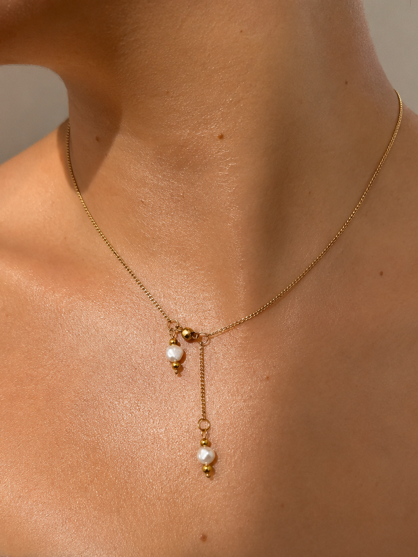 Close-up of a gold dual pearl pendant necklace with two white baroque freshwater pearls worn on the neck
