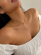 Woman wearing an asymmetrical gold necklace with two white baroque freshwater pearl pendants