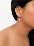 Woman wearing a gold drop earring with a 10 mm white baroque freshwater pearl.