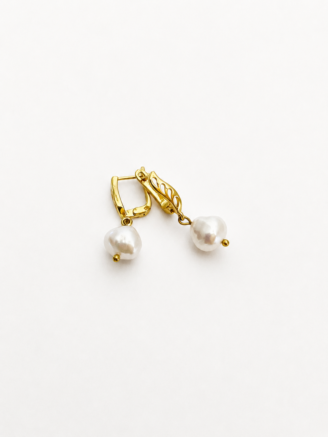 Pair of gold drop earrings with 10 mm white baroque freshwater pearl pendants.
