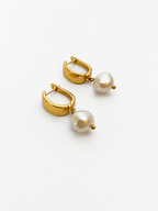 Pair of gold huggie hoop earrings with 10 mm white baroque freshwater pearl drops.