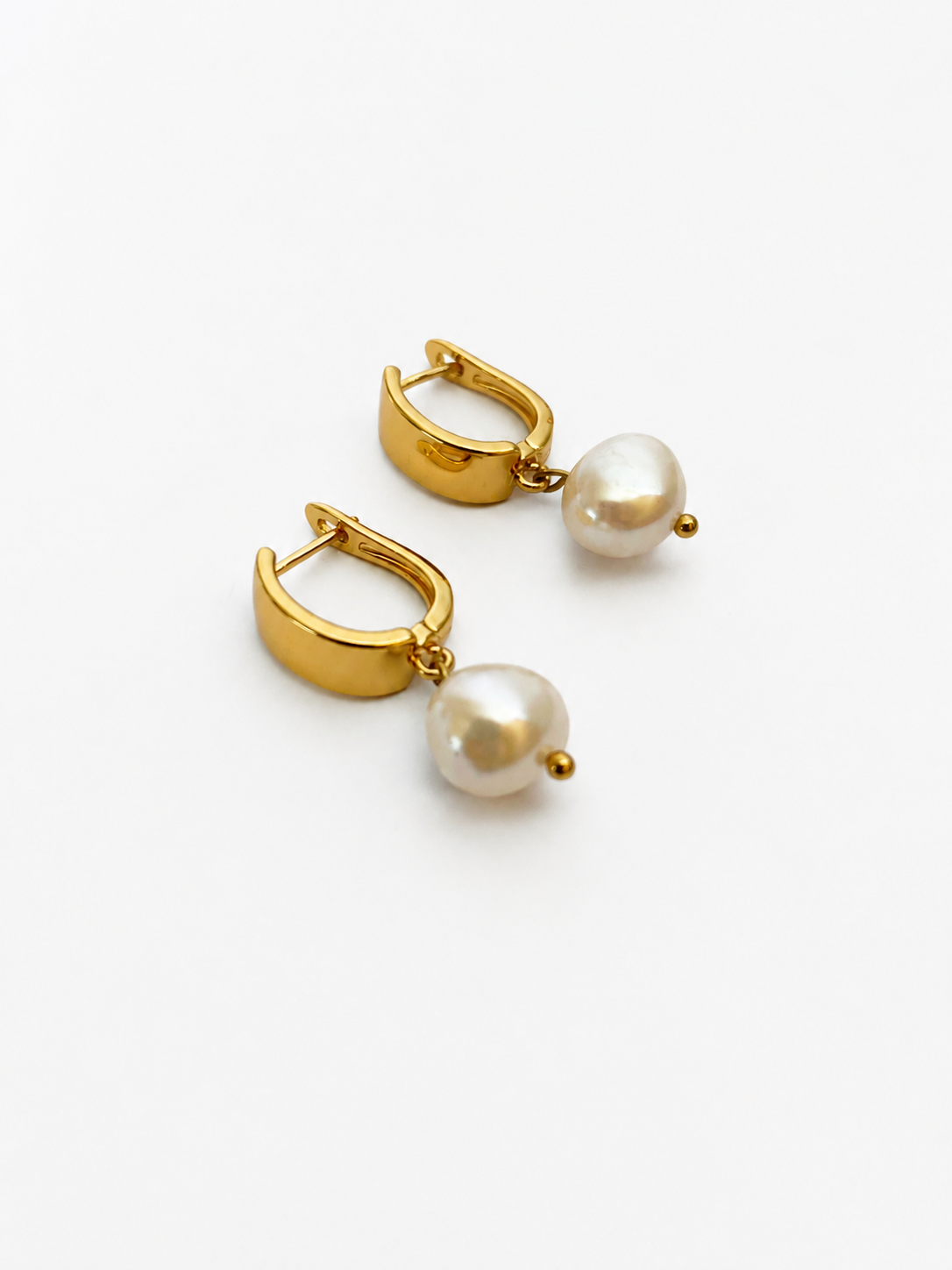 Pair of gold huggie hoop earrings with 10 mm white baroque freshwater pearl drops.