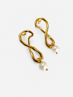 Angled pair of sculptural gold knot drop earrings with 10 mm white baroque freshwater pearls.