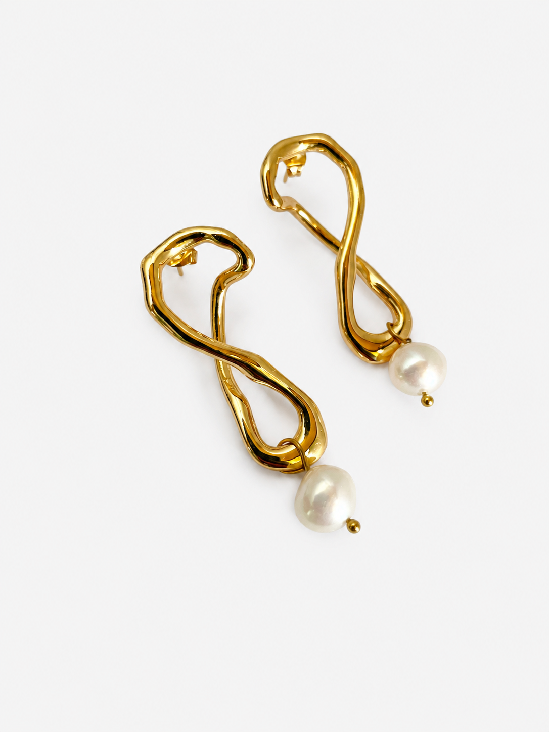 Angled pair of sculptural gold knot drop earrings with 10 mm white baroque freshwater pearls.