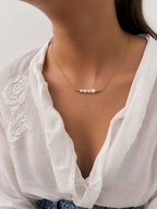 Close-up of a gold necklace with 6 mm white baroque freshwater pearls worn on the neck.