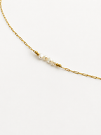 Woman wearing a gold chain necklace with white baroque freshwater pearls and polished gold beads