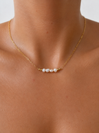 Woman wearing a gold chain necklace with white baroque freshwater pearls and polished gold beads.