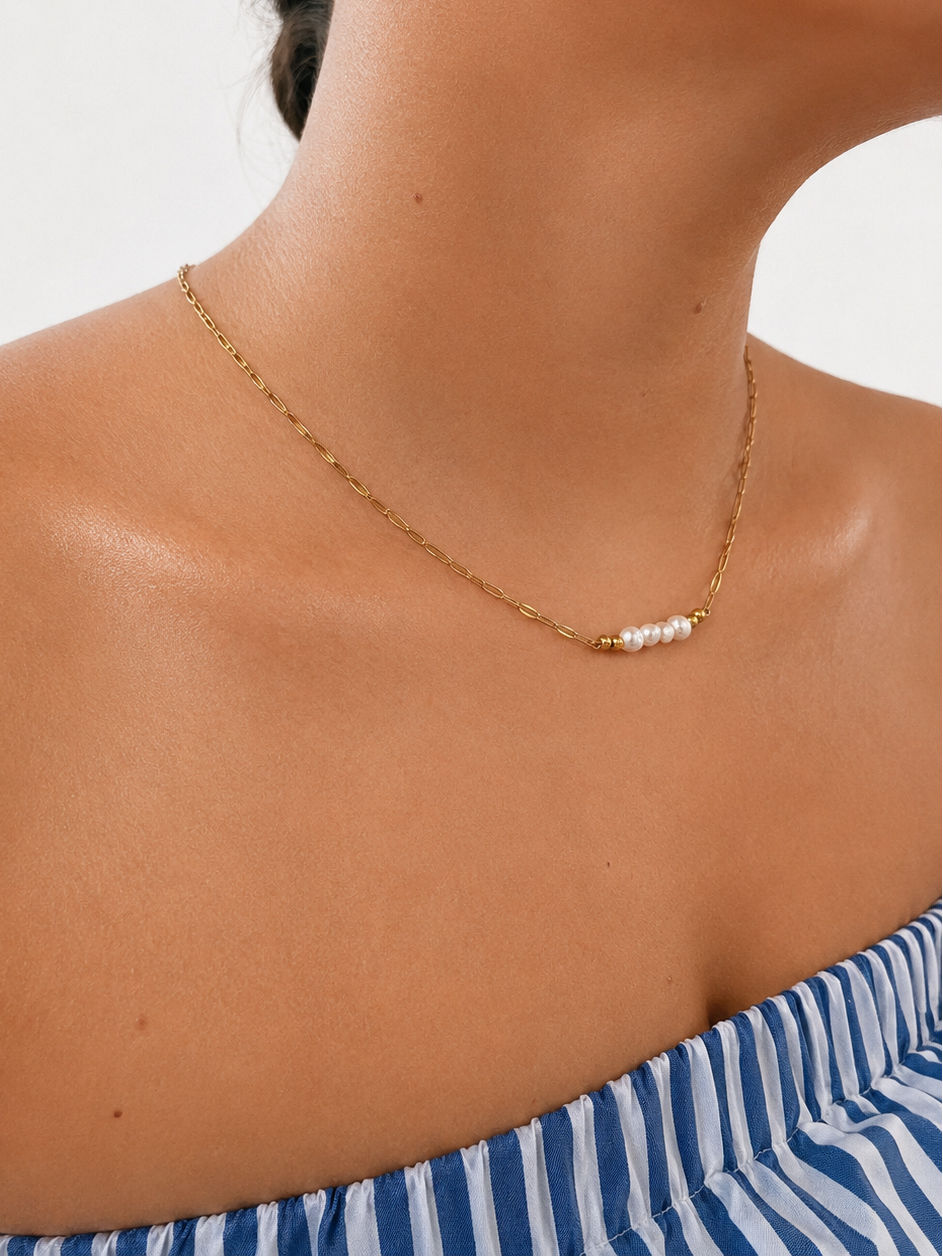 Woman wearing a delicate gold necklace with 6 mm white baroque freshwater pearls.