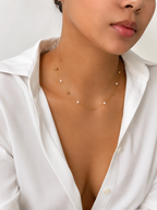 Woman wearing a gold rose station necklace with 4 mm white baroque freshwater pearls