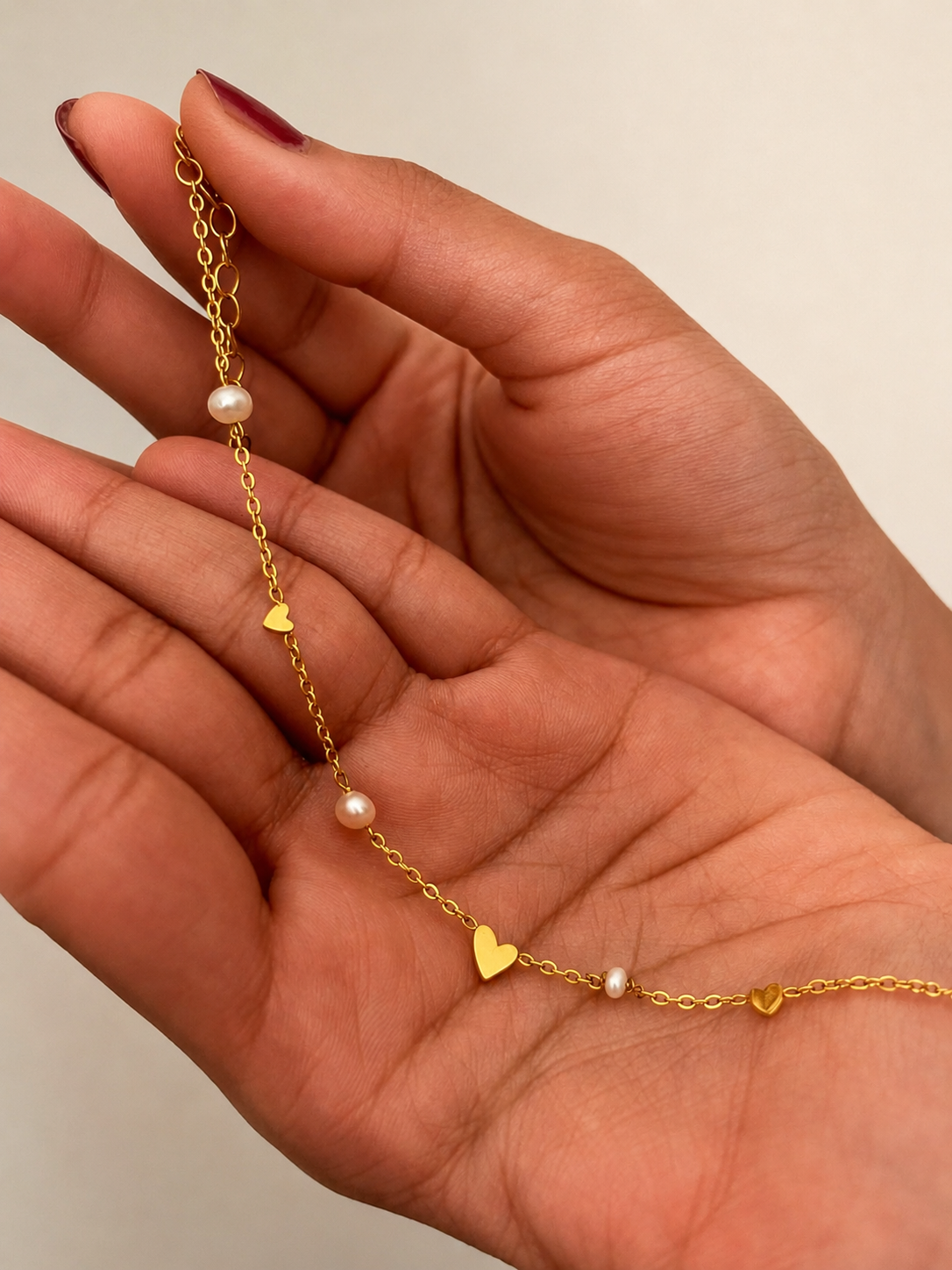 Close-up of a gold heart bracelet with white baroque freshwater pearls and an adjustable extension chain