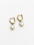 Front view of gold huggie hoop earrings with organic white baroque freshwater pearl drops.