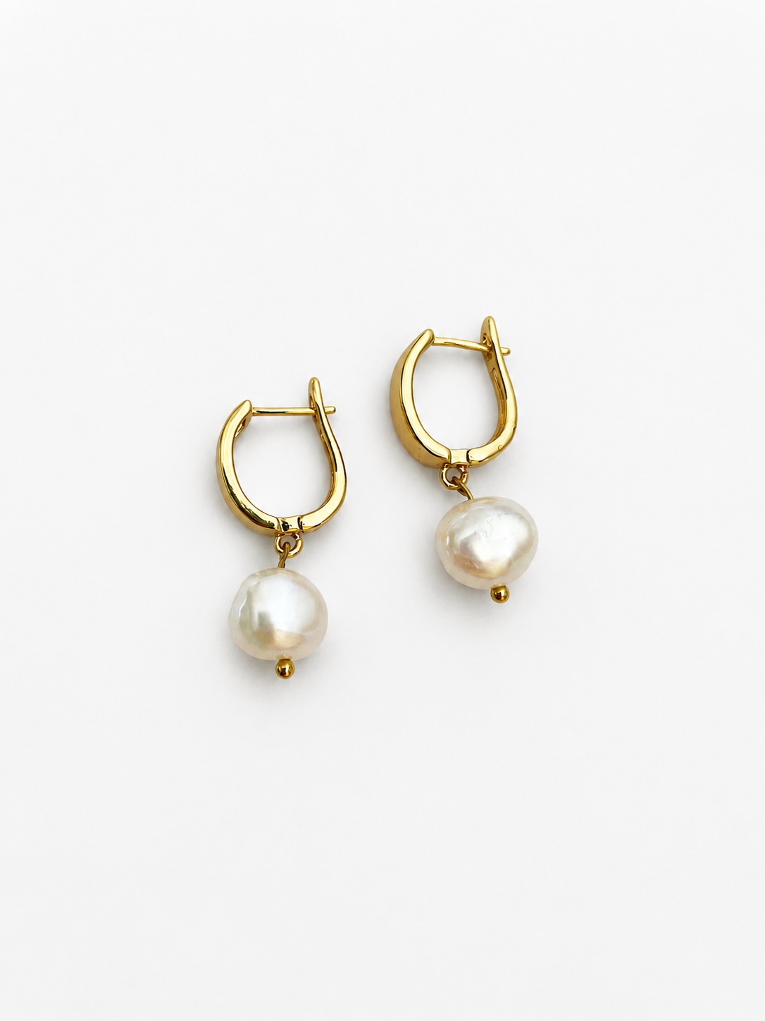 Front view of gold huggie hoop earrings with organic white baroque freshwater pearl drops.