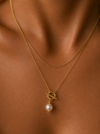 Close-up of a gold lariat Y-necklace with a 10 mm white baroque freshwater pearl and toggle detail worn on the neck