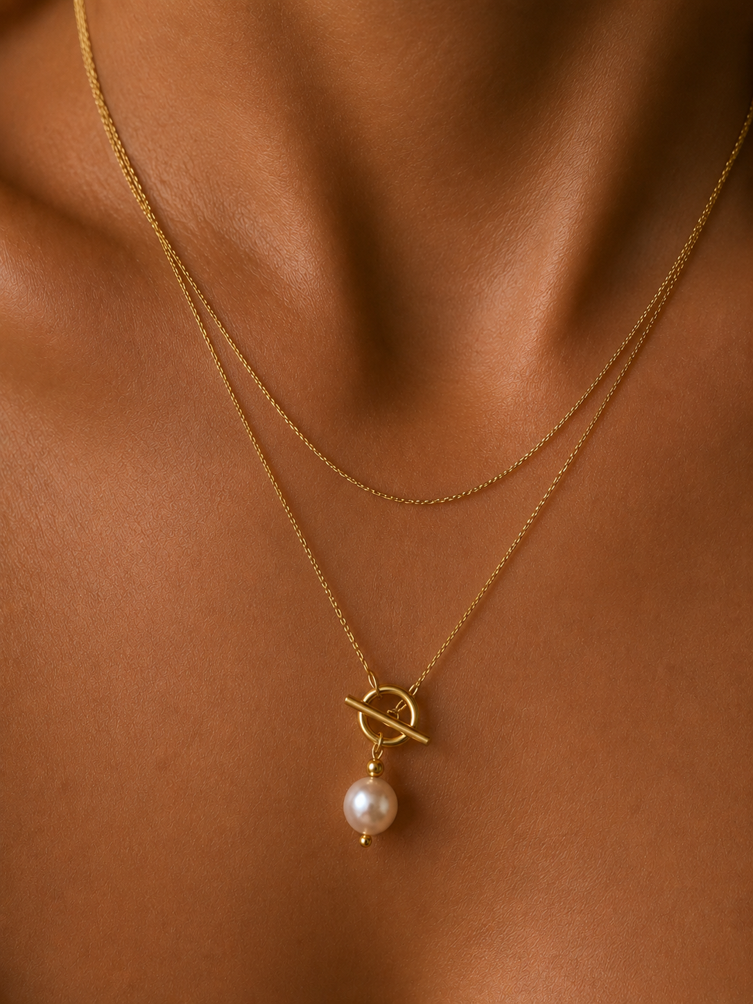 Close-up of a gold lariat Y-necklace with a 10 mm white baroque freshwater pearl and toggle detail worn on the neck