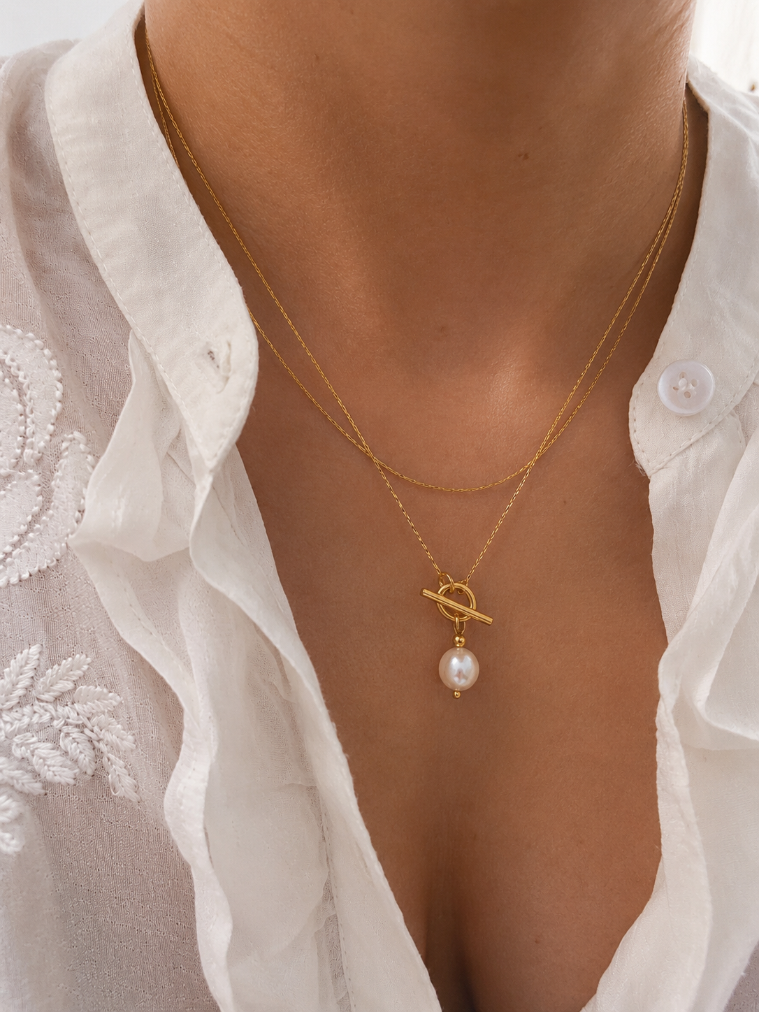 Woman wearing a gold lariat Y-necklace with a 10 mm white baroque freshwater pearl pendant
