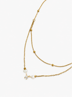 Close-up of a gold layered beaded necklace with two white baroque freshwater pearls and a cubic zirconia solitaire pendant.