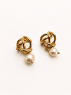 Pair of gold love knot drop earrings with 10 mm white baroque freshwater pearls.