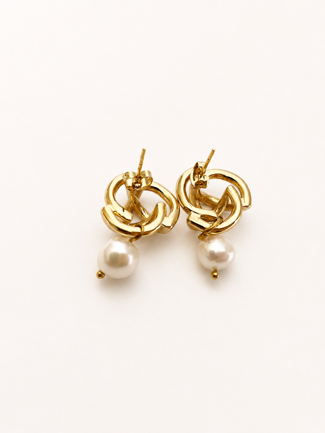 Back view of gold love knot drop earrings with white baroque freshwater pearl pendants and stud posts