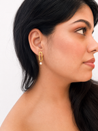 Woman wearing a textured gold stud earring with a 6 mm white baroque freshwater pearl drop