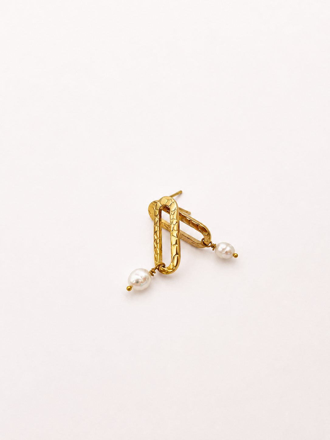 Angled pair of textured gold stud earrings with organic white baroque freshwater pearl drops.