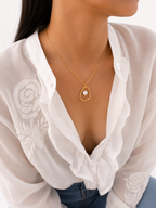 Woman wearing a gold molten pendant necklace with a white baroque freshwater pearl.