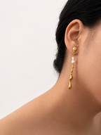Close-up of a gold Molten River earring with 4 mm white baroque freshwater pearls worn on the ear