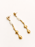 Angled view of sculptural gold Molten River earrings with 4 mm white baroque freshwater pearl drops