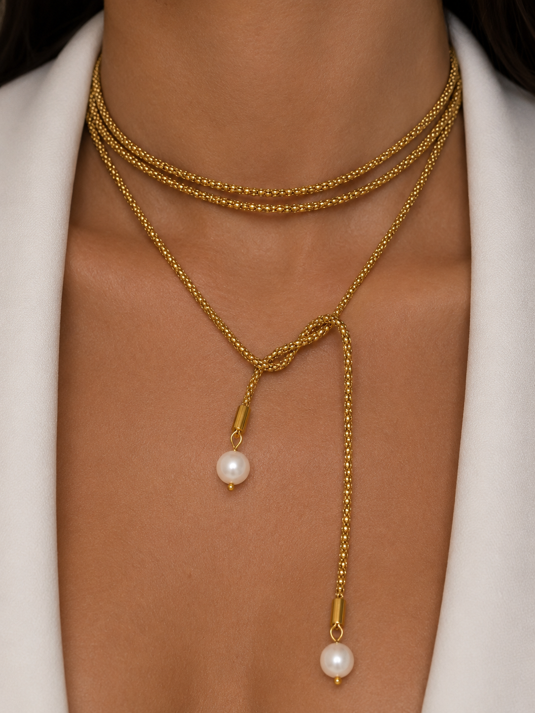 Close-up of a gold open beaded necklace with two white baroque freshwater pearl drops worn on the neck