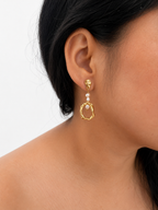 Close-up of a sculptural gold droplet earring with white baroque freshwater pearls worn on the ear