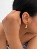 Woman wearing a sculptural gold organic droplet earring with 4 mm white baroque freshwater pearls.
