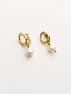 Angled view of gold pebble drop earrings with 10 mm white baroque freshwater pearl drops.