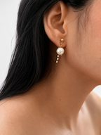 Close-up of a gold Siren drop earring with a 10 mm white baroque freshwater pearl and crystal accents