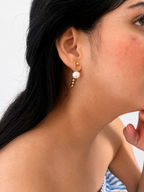 Woman wearing a gold Siren drop earring with a white baroque freshwater pearl and crystal accents