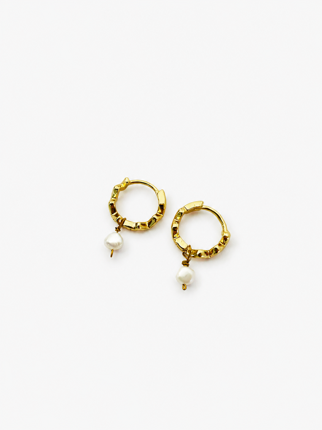 Angled view of small gold creole earrings with 4 mm white baroque freshwater pearl drops.