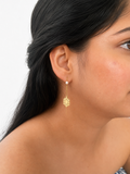Woman wearing a gold snowflake drop earring with a 4 mm white baroque freshwater pearl.