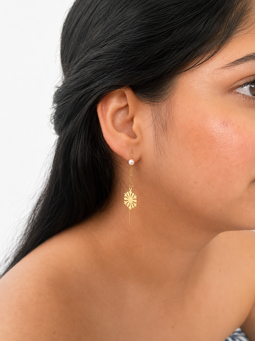 Woman wearing a gold snowflake drop earring with a 4 mm white baroque freshwater pearl.