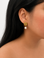 Woman wearing a textured gold square stud earring with a white baroque freshwater pearl drop
