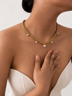 Lifestyle view of a gold statement charm necklace with a white baroque pearl and smaller white freshwater pearls