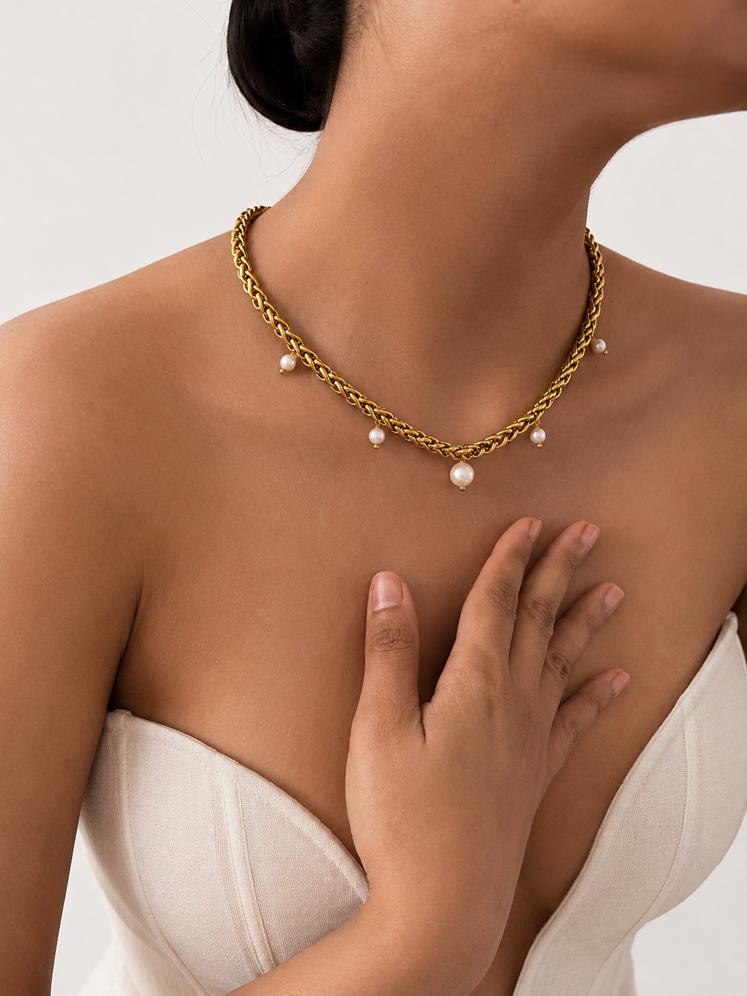 Lifestyle view of a gold statement charm necklace with a white baroque pearl and smaller white freshwater pearls